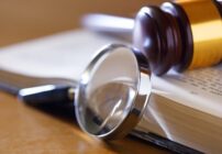 A gavel, magnifying glass, and book being used in a federal investigation.
