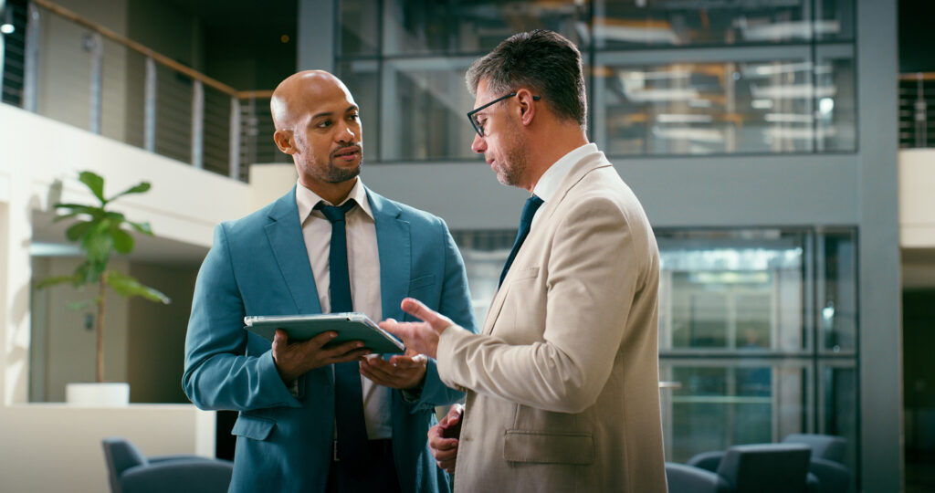 Two white collar professionals in an office setting discussing the findings of an internal audit.