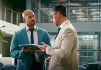 Two white collar professionals in an office setting discussing the findings of an internal audit.