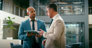 Two white collar professionals in an office setting discussing the findings of an internal audit.